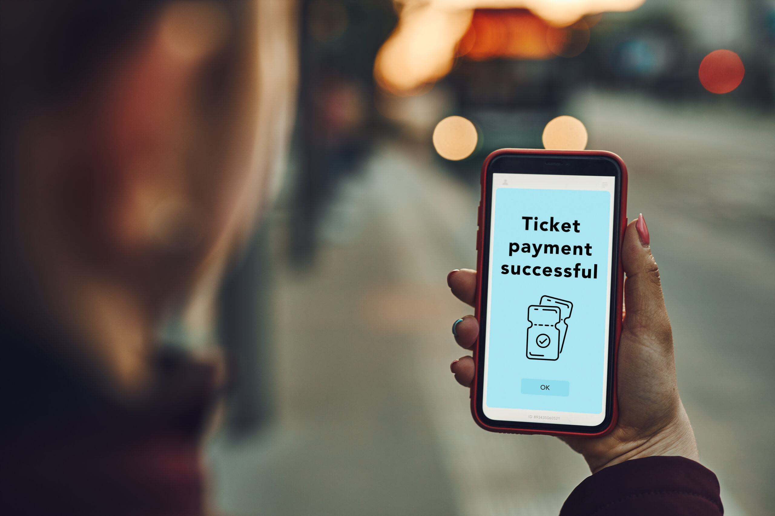 A person confirming successful mobile ticket payment on a smartphone, illustrating embedded finance in everyday life